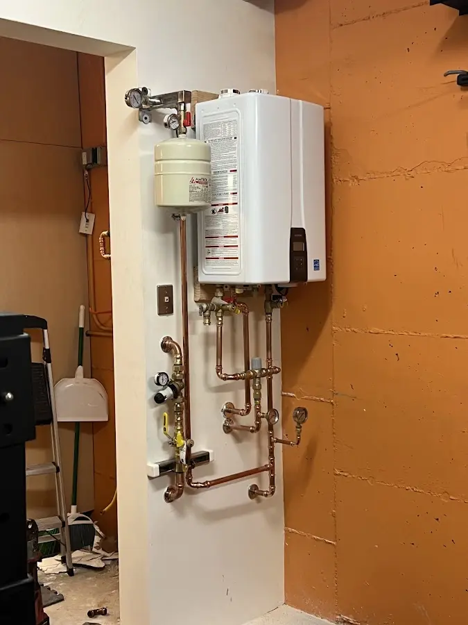 Plumbing technician inspecting water heater connections in Kennedy